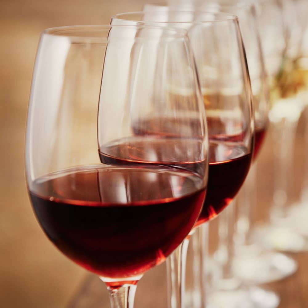 a row of wine glasses filled with red wine